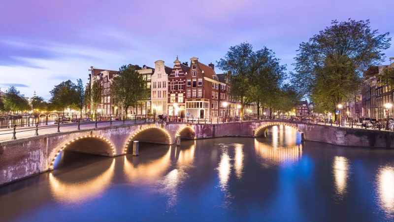 cruzeiros fluviais: canais de Amsterdã, com arcos das pontes iluminados por luzes brancas