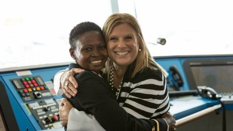 Na cabine de comando de um navio, a CEO da Celebrity Cruises, Lisa Luttoff-Perlo, abraça a cadete Nicholine Tifuh Azirh, primeira mulher negra da África Ocidental.
