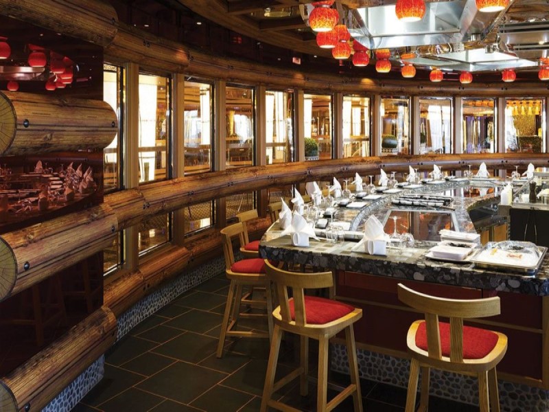 Balcão do restaurante japonês Teppanyaki do navio Costa Diadema, com cadeiras ao redor do balcão de preparação dos pratos.