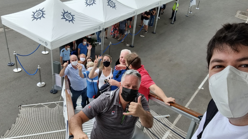 Imagem do alto da escadaria de embarque no navio de cruzeiro MSC Seaside, com viajantes subindo a bordo