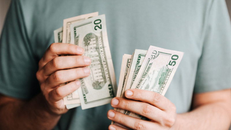 Imagem e homem com notas de dólar nas mãos, no navio de cruzeiros MSC Seaside