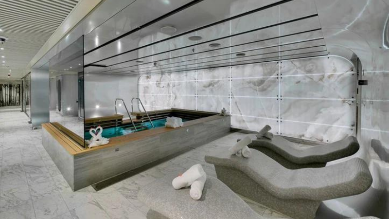 Área do Aurea Spa, no navio MSC Seaside, contendo piscina e cadeiras espreguiçadeiras.