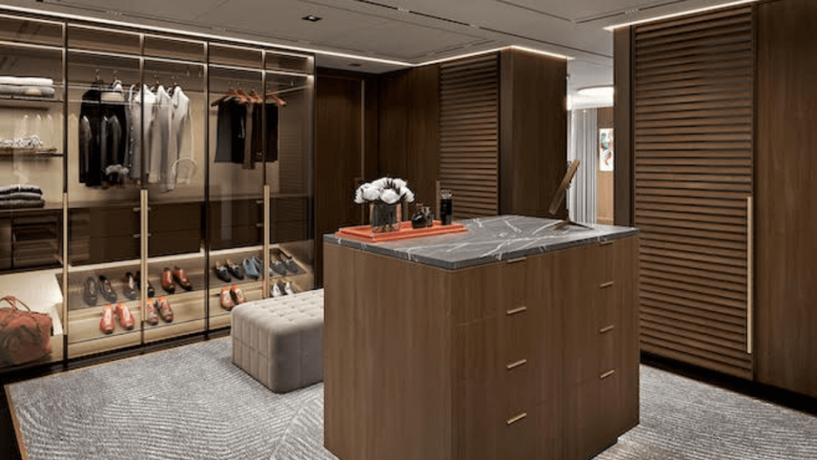 Um amplo closet com ilha central e armários com frente de vidro oferece amplo espaço de armazenamento