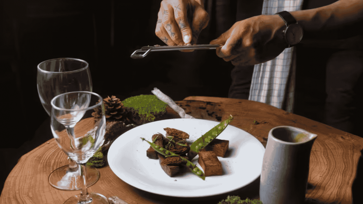 Um chef dá os toques finais a um prato de caribu servido com chá-do-labrador.
